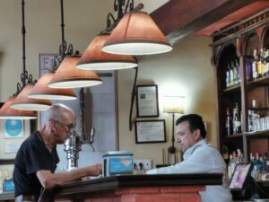 Manfred paying for our meal and chatting with the barman at Taberna El Tabanco, Hotel Alcázar De La Reina, Carmona