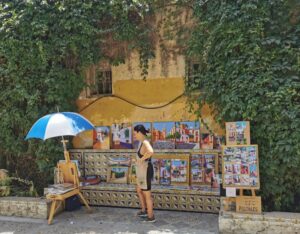 The street artist with her work near the entrance to Barrio Santa Cruz
