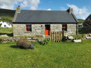 A stone house with a sheep sculpture outside the gate Dugort Beach, Achill Island