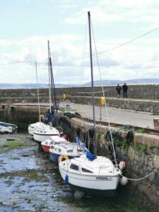 Boats lined up at Bearna Harbour with people walking on the high path