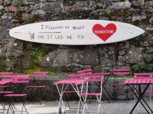 Cafe tables and a surfboard sign in Roundstone