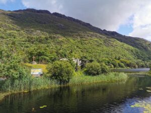 The Gaelic Irish Cross, the signboard of the gardens near Kylemore Abbey in the trees below the steep hills beyond