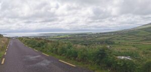 The narrow road and the view down into Dingle Bay and the Ring of Kerry under cloud beyond