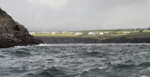 The sun shines on the houses above Dingle Bay's choppy waters