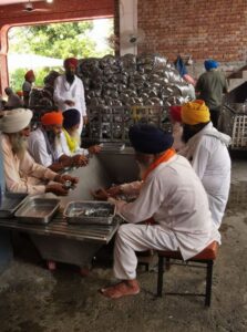 Volunteer men washing drying and sorting cutlery in the Ramgarhia Bunga Langar