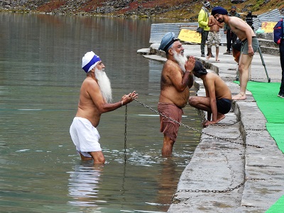 Sikh pilgrims paying homage at the lake edge - the chain is so they don't fall in