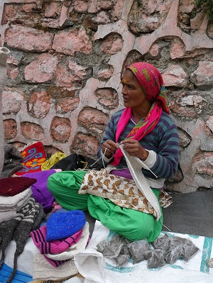 Local Mana lady knitting and selling her wool hats and socks. Himalayas, India