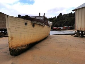 The boat houses in sheltered Golden Bay and an old boat pulled up on the sand