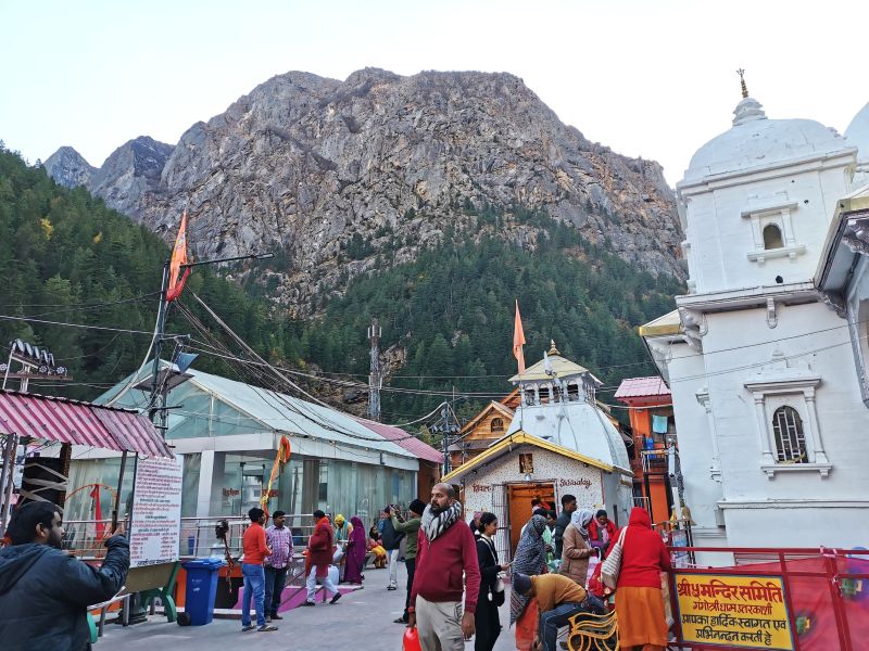 To the side of the Gangotri Temple, the steps down to the river, the entrance to the complex and the mountains up beyond