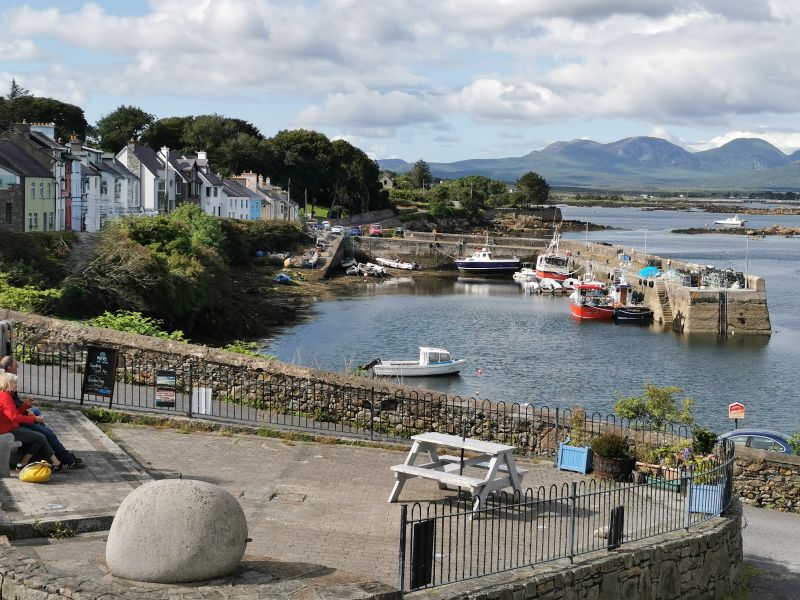 A couple sitting near the harbour and entrance road, Roundstone