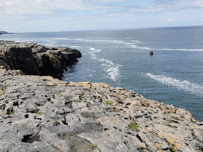 A fishing boat below the cliffs in The Burren