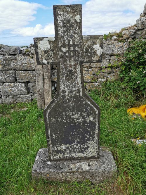 A grave with faded inscriptions and a sign indicating devotion to Jesus Christ