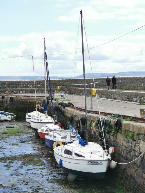 Boats lined up at Bearna Harbour with people walking on the high path