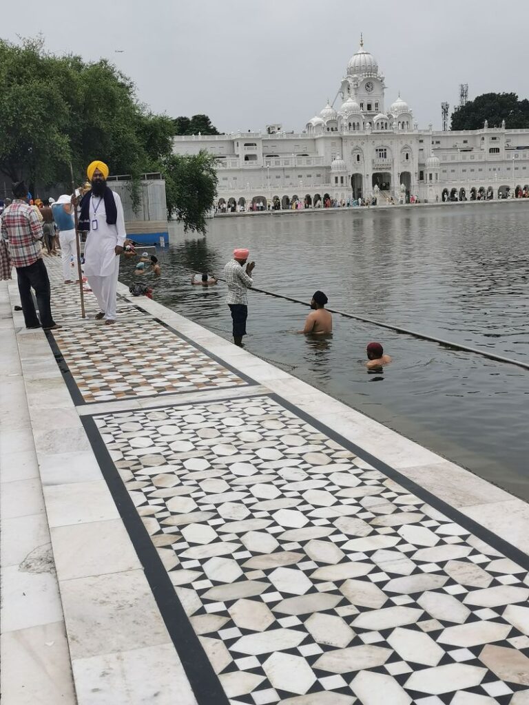 Pilgrims take a ceremonial dip in the Amrit Sarovar as a guard walks by